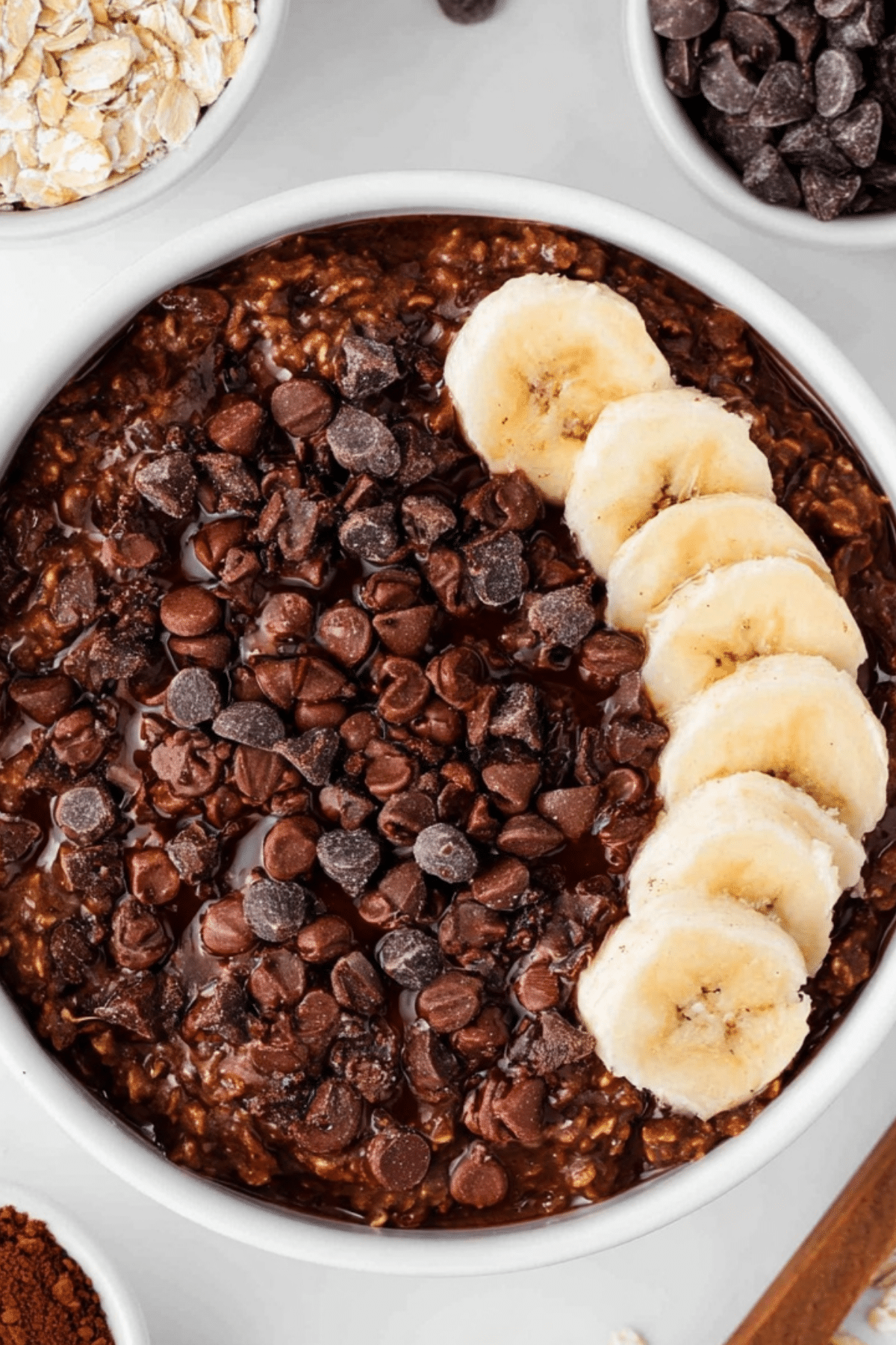 chocolate oatmeal with berries and nut butter in a white bowl