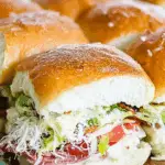 Italian Grinder Sliders on a plate with melted cheese and savory meats