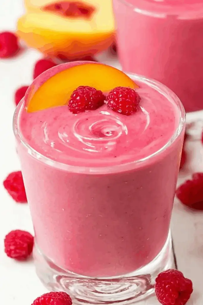 Raspberry Peach Smoothie served in a glass with fruit