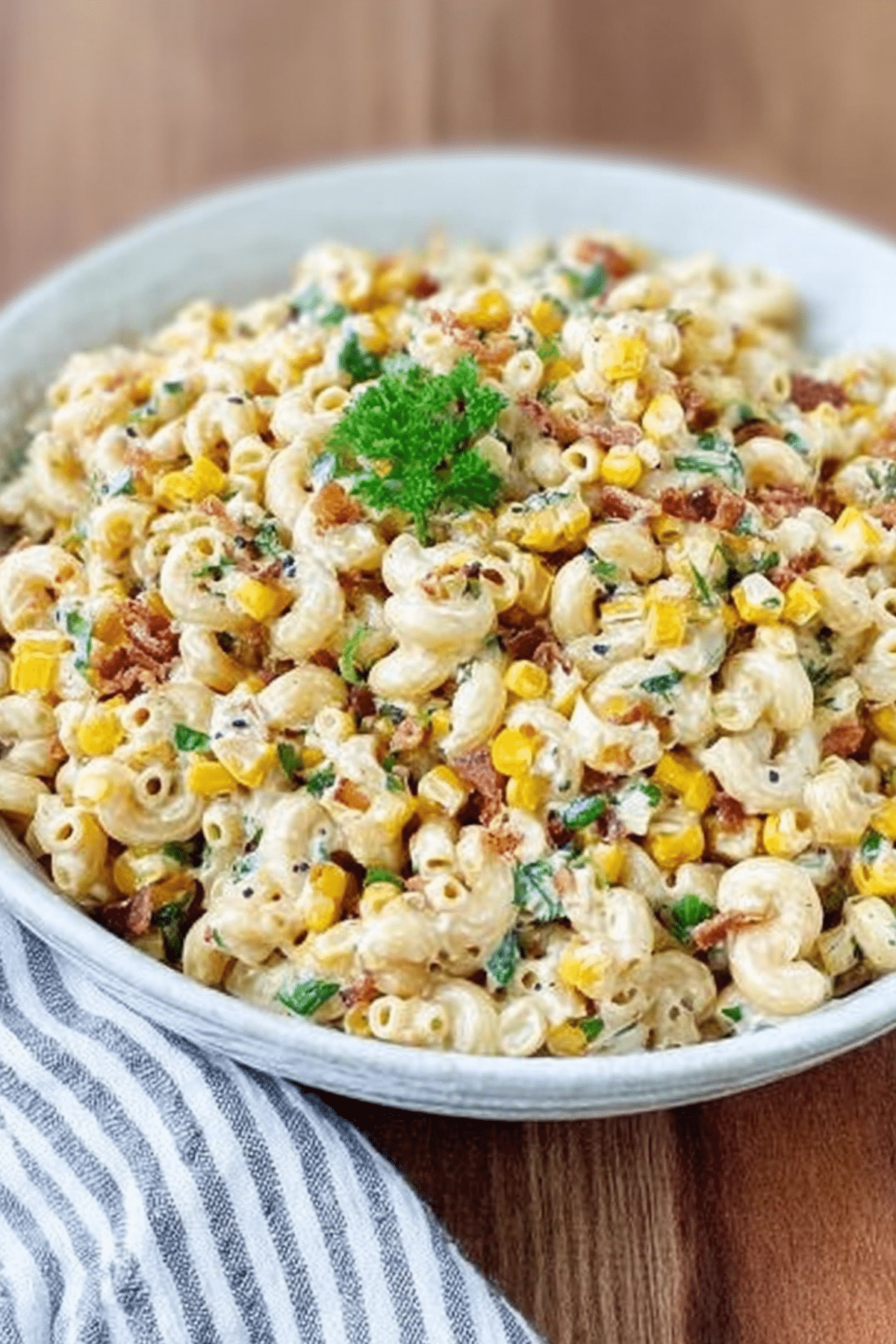Crack Corn Pasta Salad with Bacon served in a bowl with fresh parsley garnish