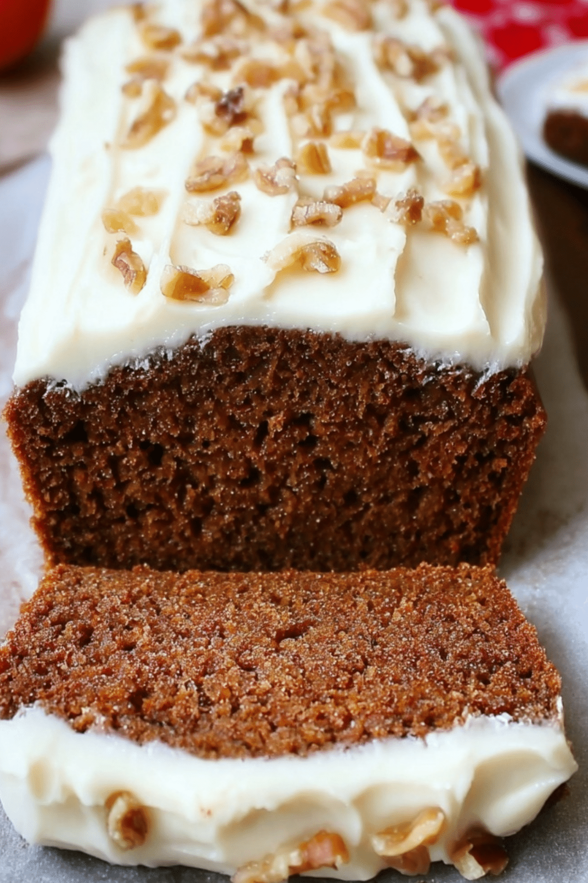 Gingerbread loaf with cream cheese frosting sliced on wooden board