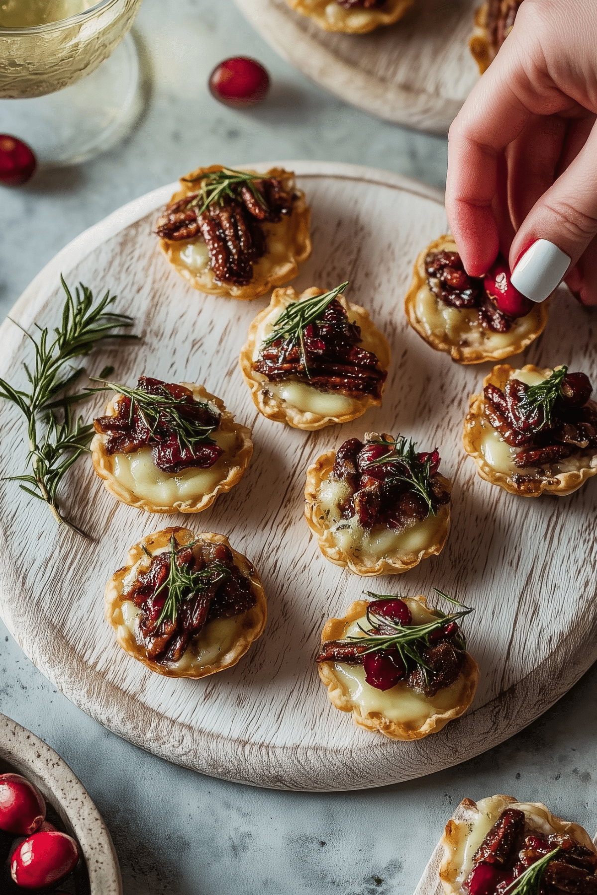 Cranberry Brie Tartlets served on a plate with fresh rosemary