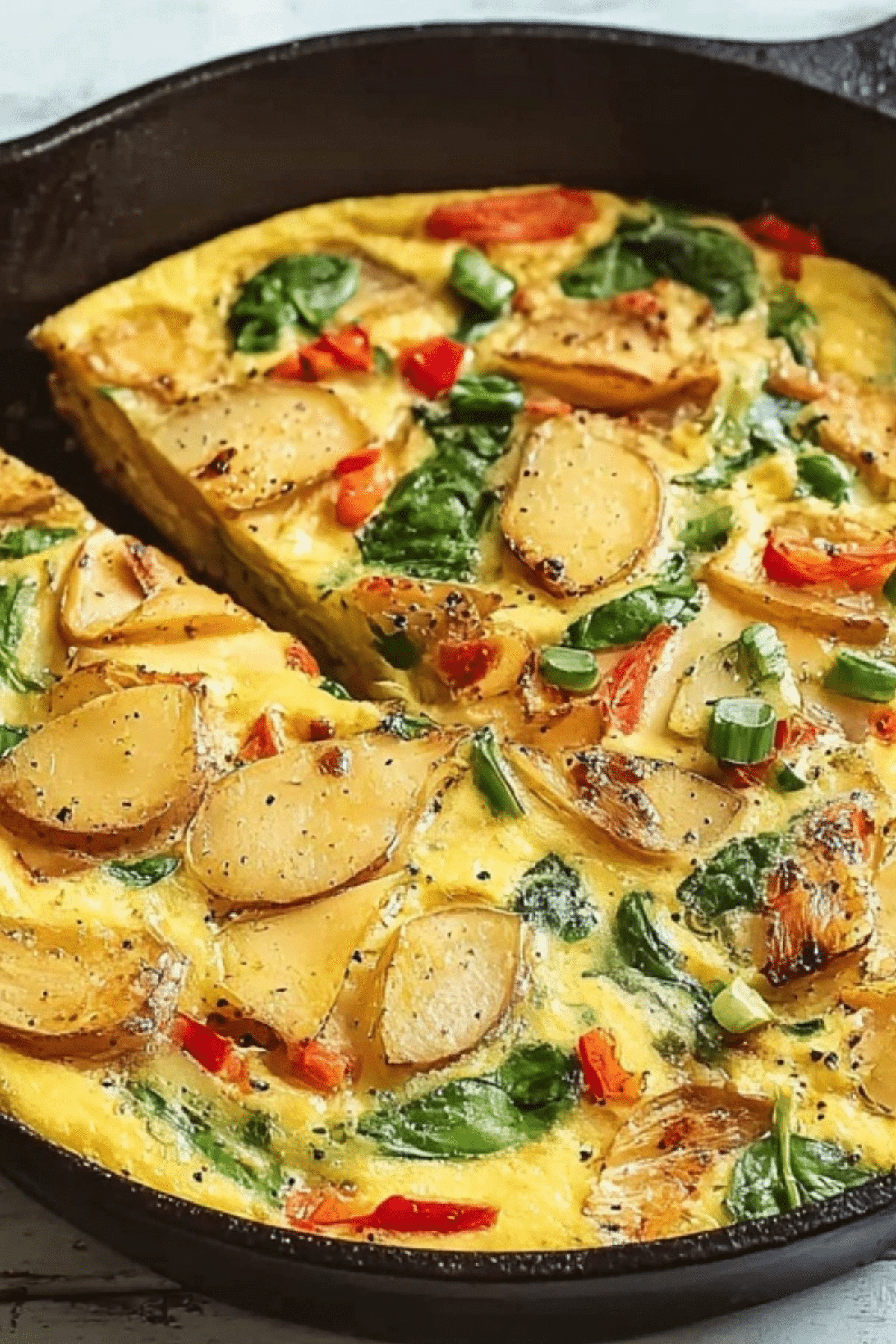 Frittata with potatoes, red peppers, and spinach served in skillet