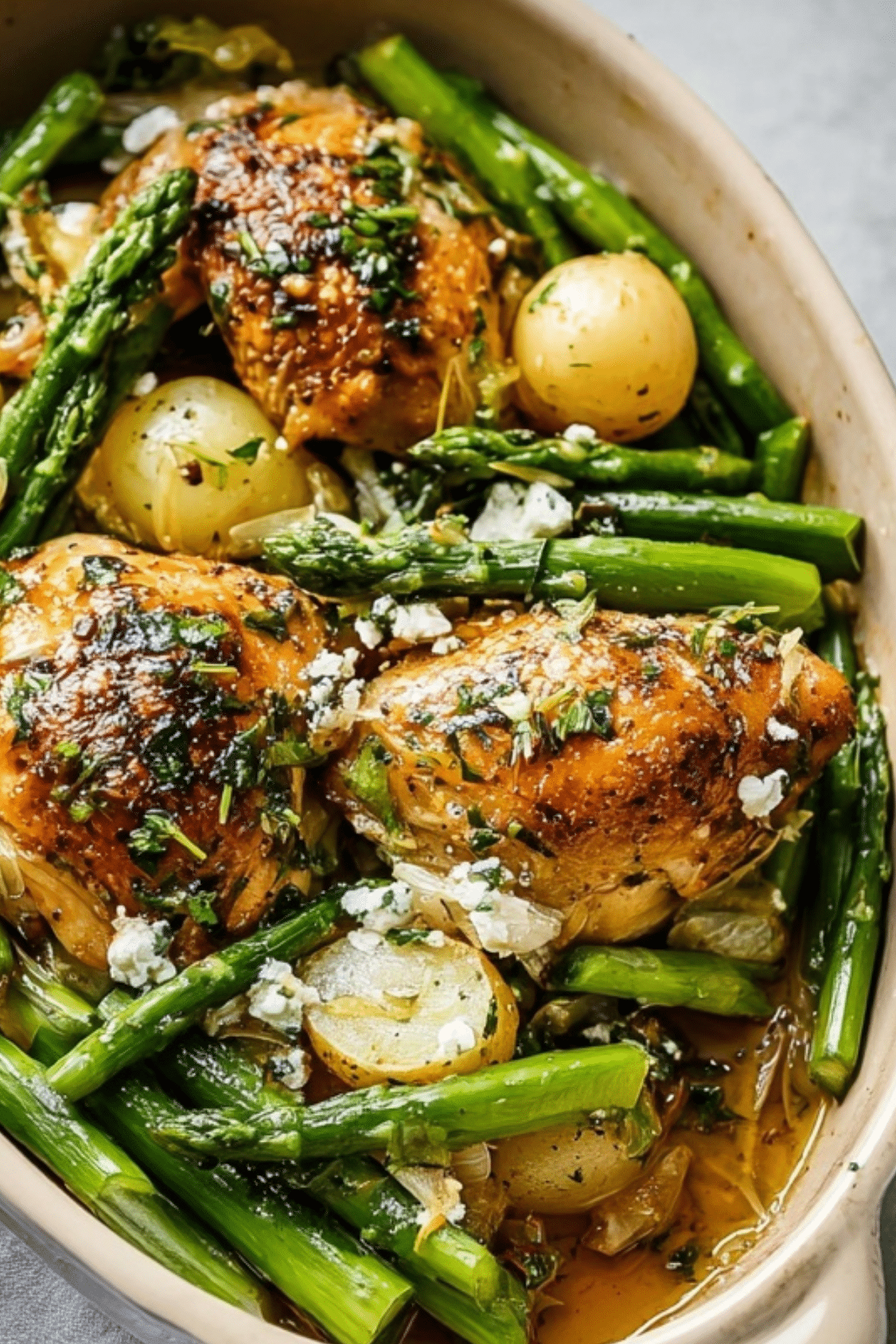 Herb Roasted Chicken With Spring Veggies served on a sheet pan with lemon and fresh herbs