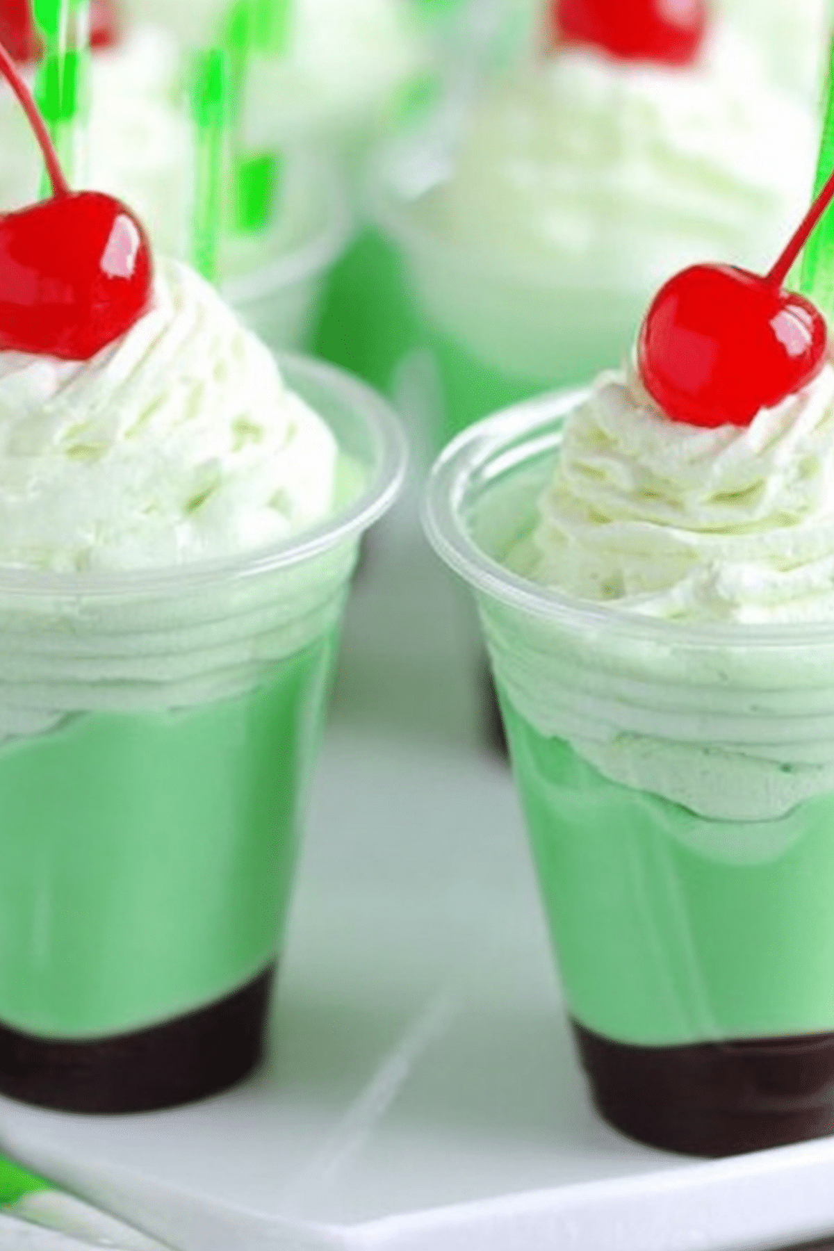 Shamrock Shake Pudding Shots topped with whipped cream and cherry