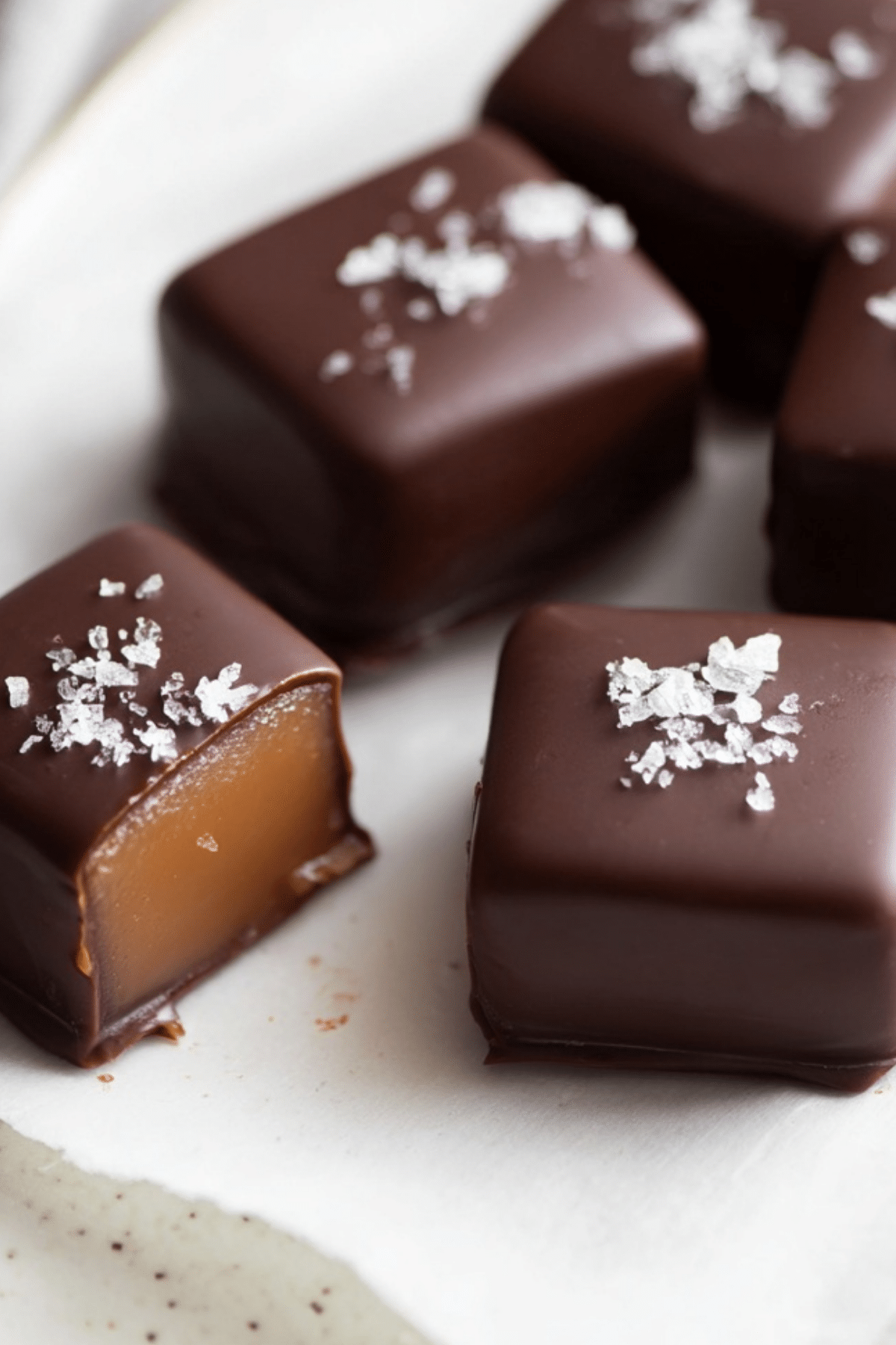 homemade chocolate covered caramels with sea salt on parchment paper